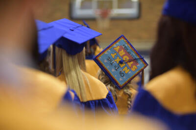 Graduating students in blue and gold gowns face forward.