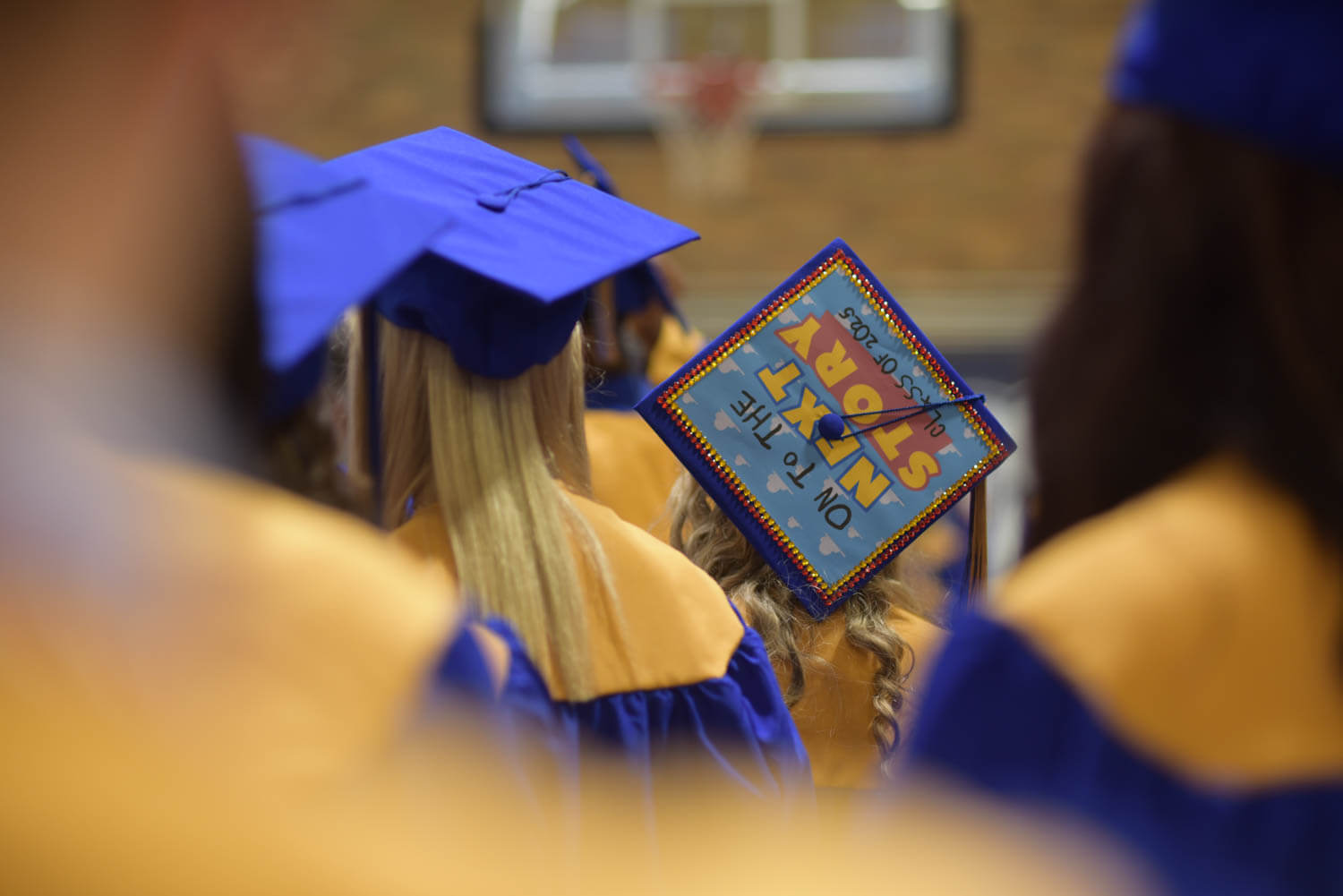 Graduating students in blue and gold gowns face forward.